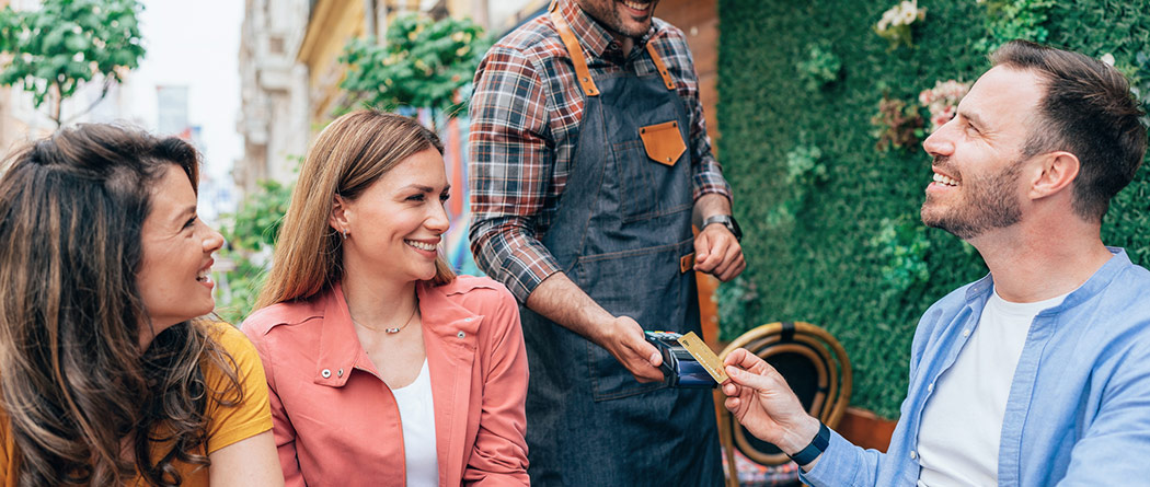 Man paying for food with his card while at dinner with friends