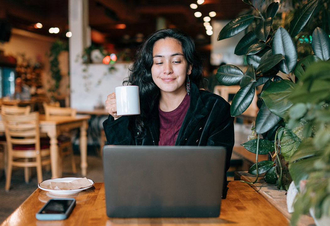 Woman smiling in cafe while working on her laptop