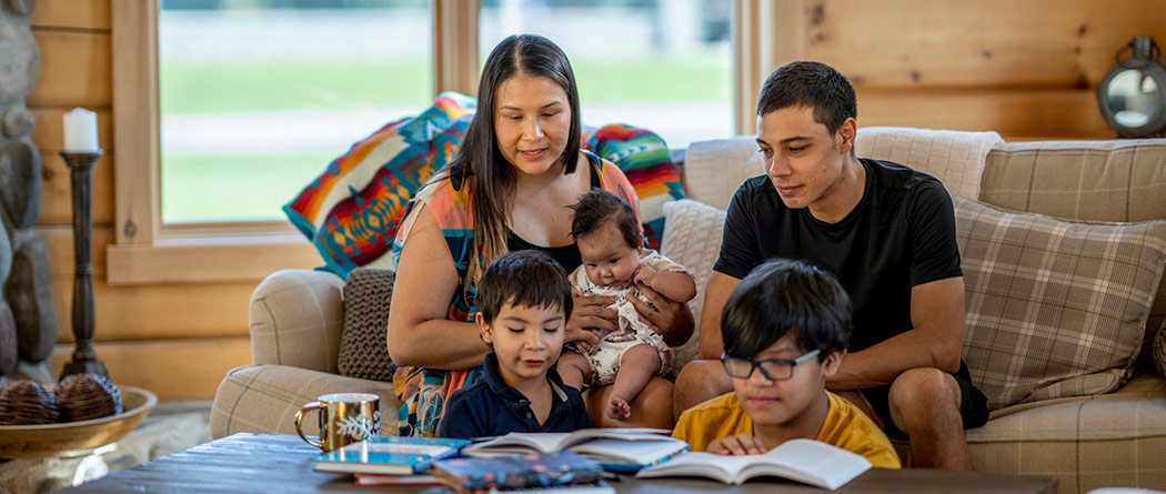 Family of 5 sitting in living room reading together