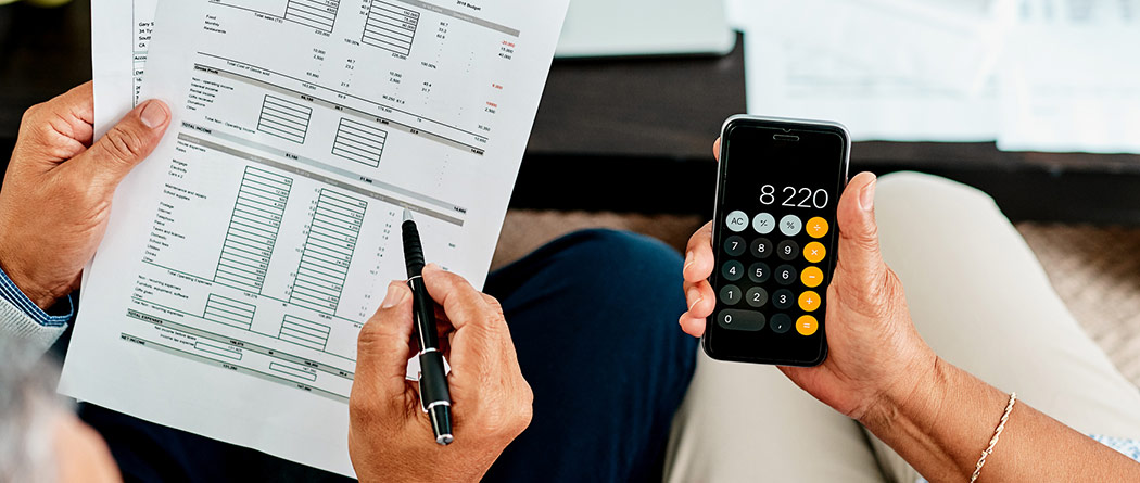 People working with a calculator while reviewing spreadsheet data